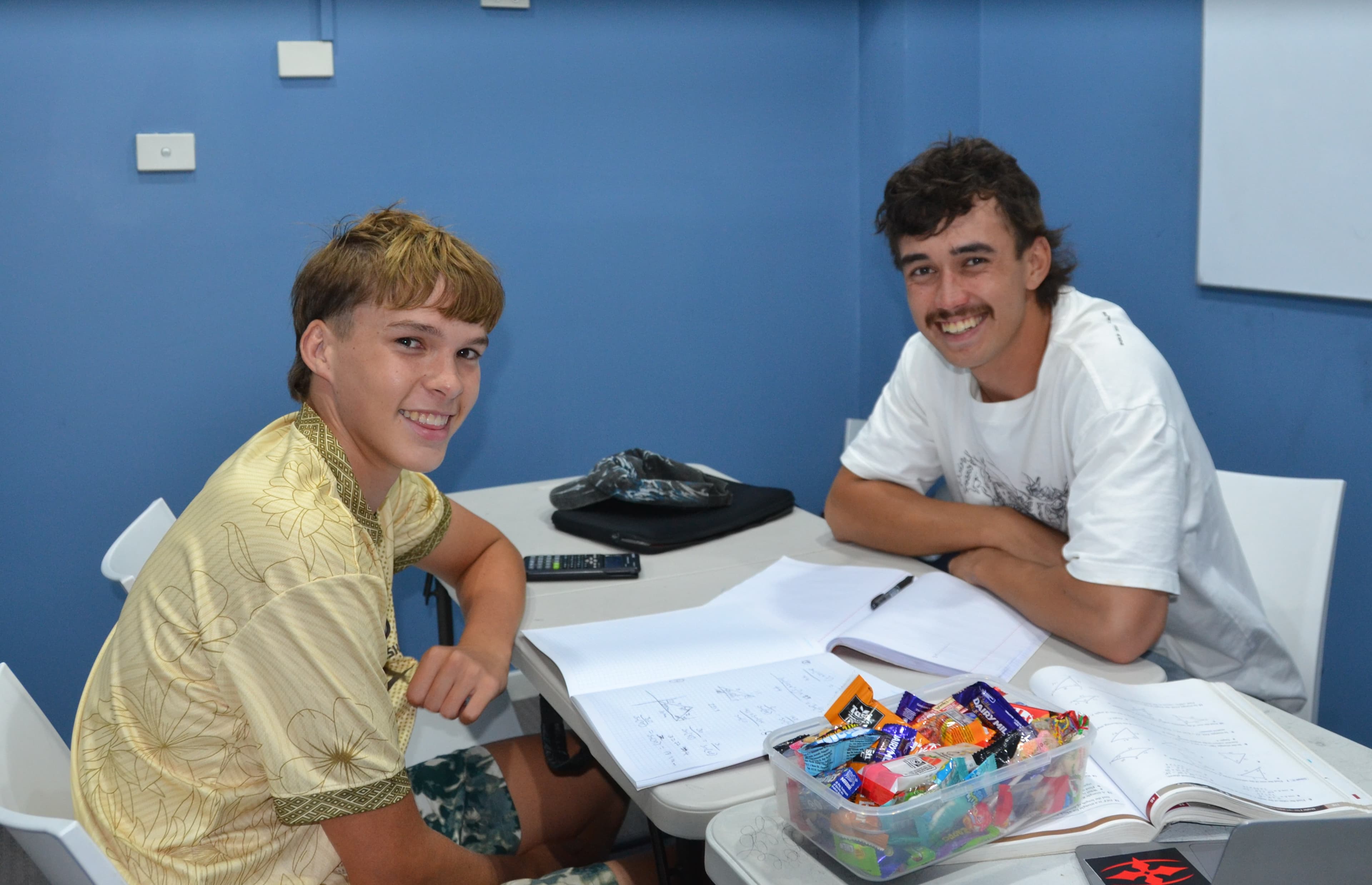 A First Education tutor and a Year 8 student sitting together at a centre desk with worksheets and study materials.